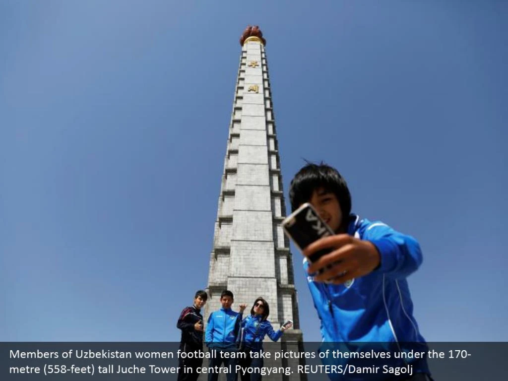 Members of Uzbekistan women football team take pictures of themselves under the 170-metre (558-feet) tall Juche Tower in central Pyongyang. REUTERS/Damir Sagolj