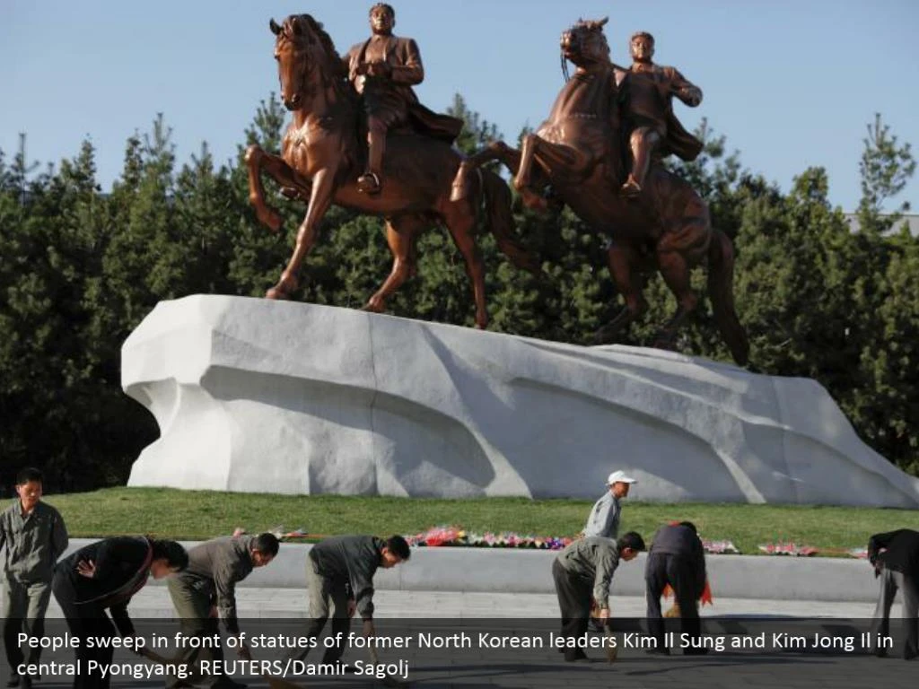 People sweep in front of statues of former North Korean leaders Kim Il Sung and Kim Jong Il in central Pyongyang. REUTERS/Damir Sagolj